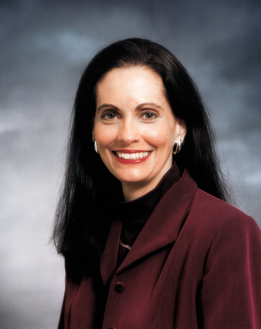 A smiling woman with dark hair and a red jacket.