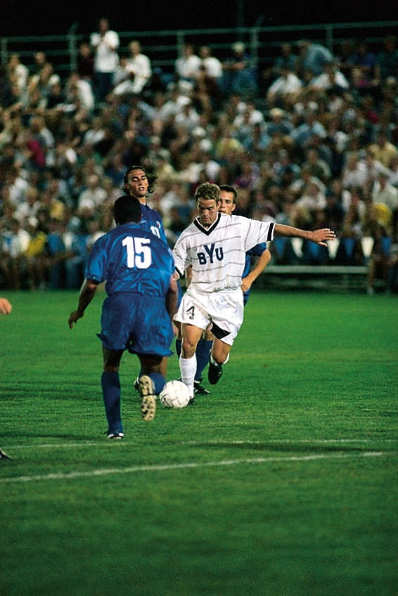 Two men on a soccer fielding competing for the ball.