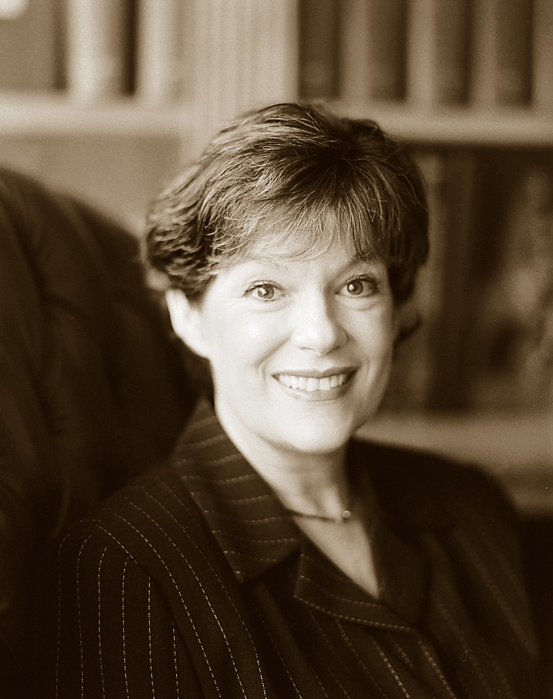 Susan Black poses in an office while wearing a dark, striped jacket.