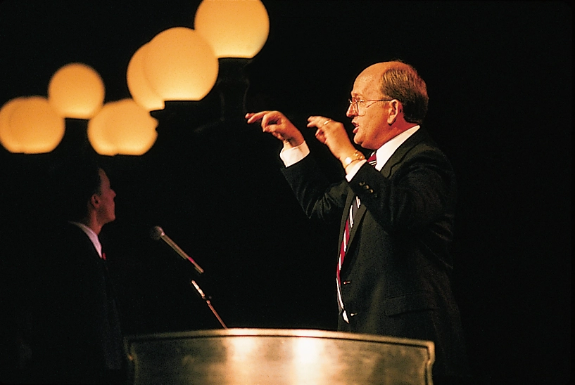 Mack Wilburg stands a a podium conducting