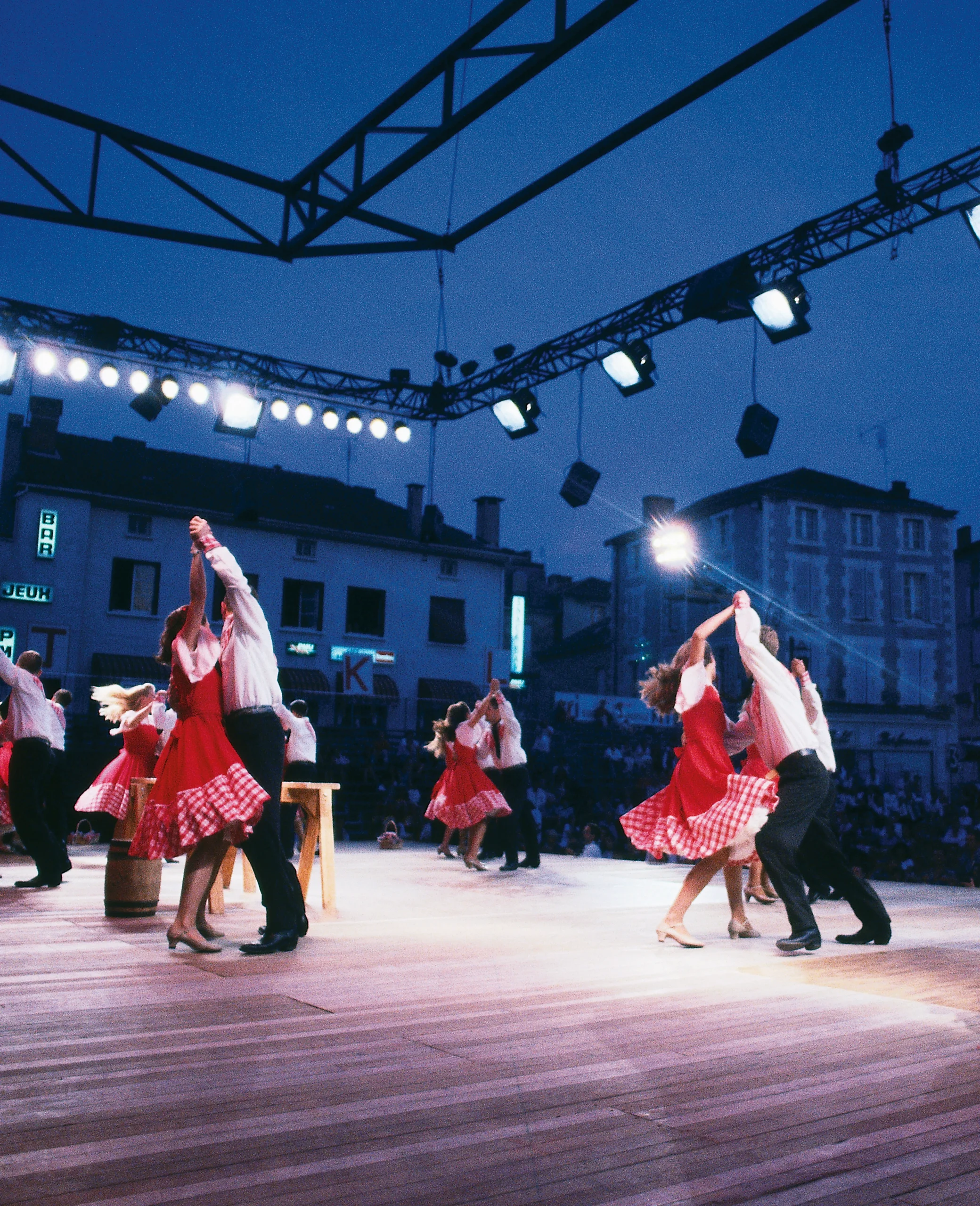 Three couples dance on a stage at evening.