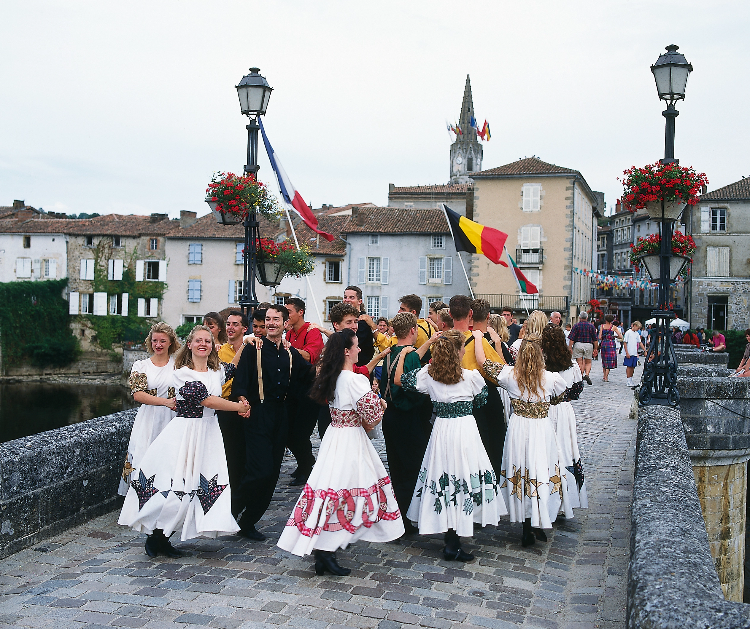 A group of performs dance on a stone bridge.