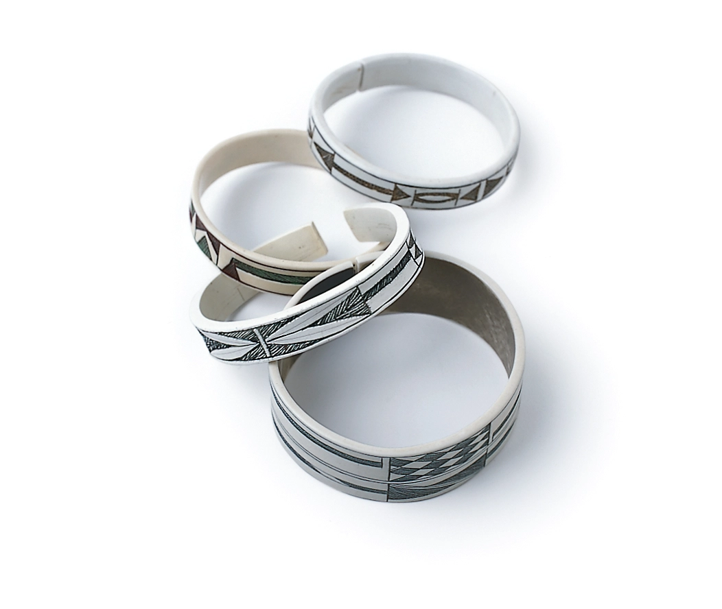 Bracelets made of pale wood bearing arrow shaped designs.