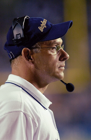 D. Gary Crowton watches a game while wearing a headset and blue hat