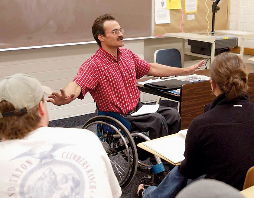 Keith W. Barney sits in a wheelchair while teaching a class.