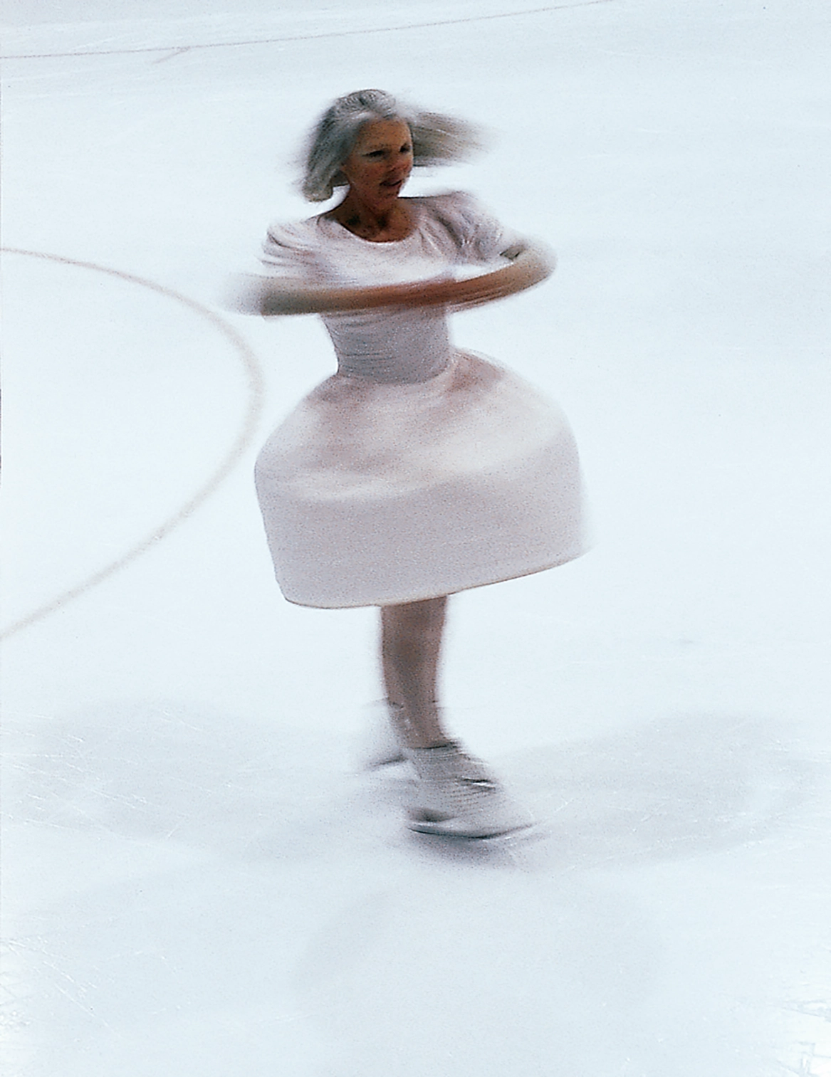 A skater in a white dress spins on the ice.