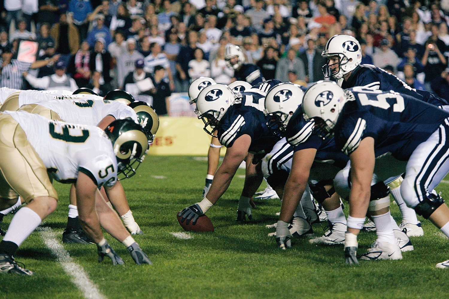 BYU football players preparing to hike the ball while facing an opposing team
