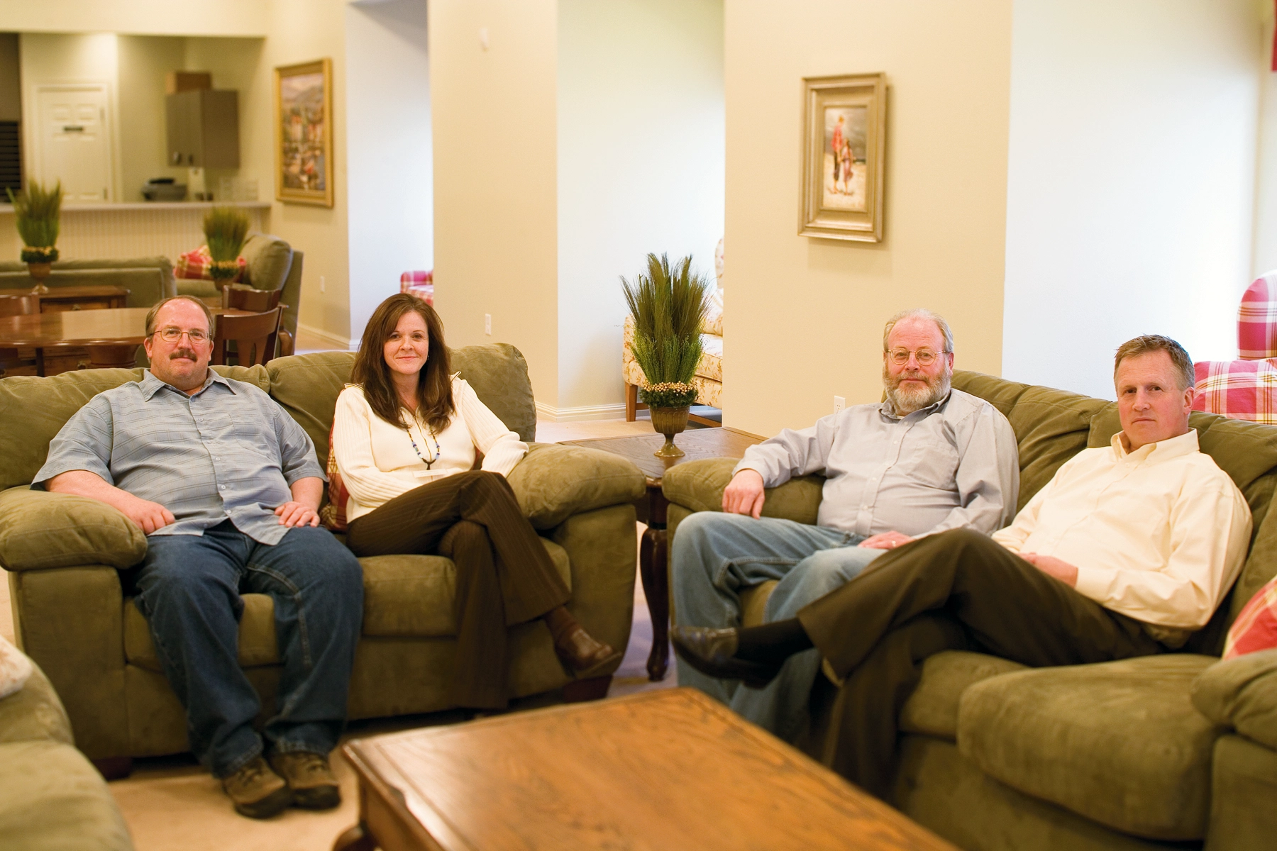 Four people sit on a couch in a living room.