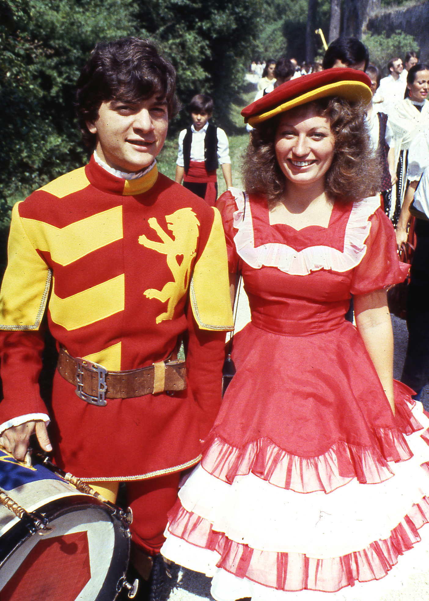 A BYU folk dancer, dressed in a red costume poses with an Italian drummer dressed in a red and yellow costume.