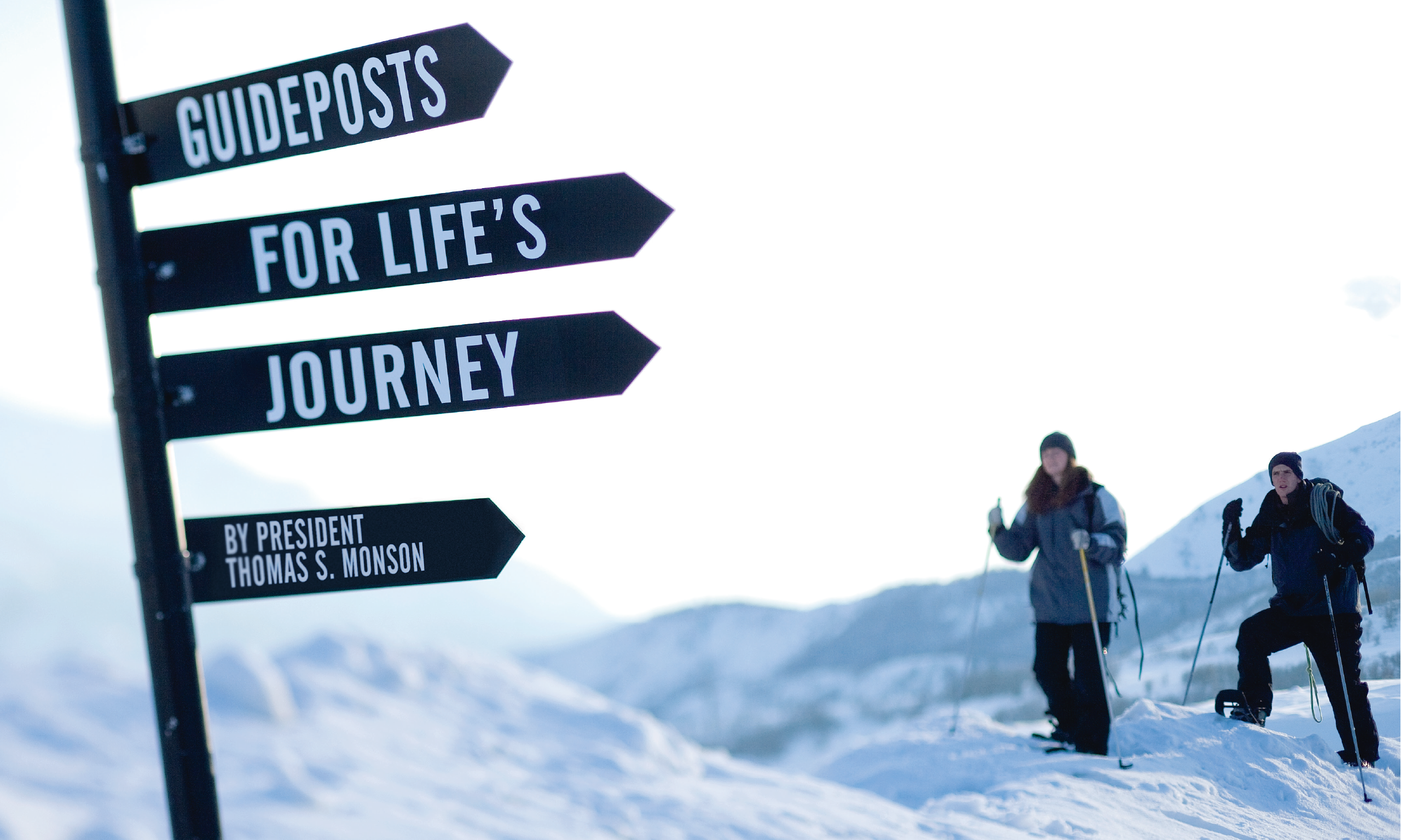 Signs in the snow read "guideposts for Life's Journey" and two skiers look to the sign for guidance.