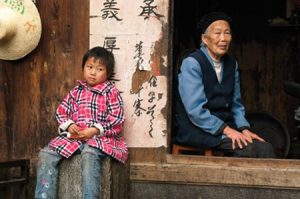 In order to support their family, many Chinese parents travel to jobs in the cities, leaving their children in the care of grandparents. John Telford observed that "Children in the more remote villages were, for the most part, seen in Western-style clothes;...the older person was typically dressed in traditional Chinese clothing." Photo by John Telford.