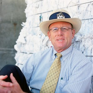 Grounds director Roy S. Peterman, '72, leans on a 1,2000-pound bale of paper at BYU's recycling facility. 