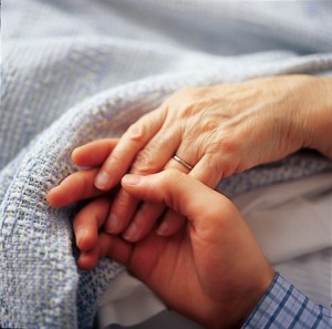 Son holding sick mothers hand