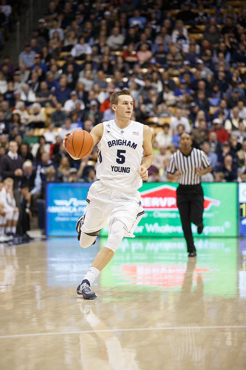 Kyle Collinsworth running down the court with the basketball in his hand.