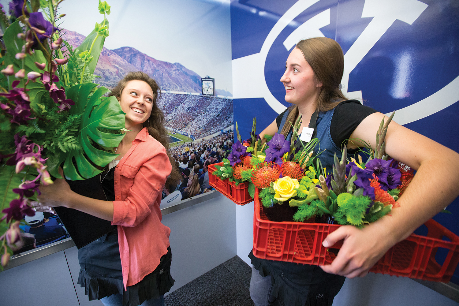 Student workers carry flower arrangements to the President's Loge at LaVell Edwards Stadium.