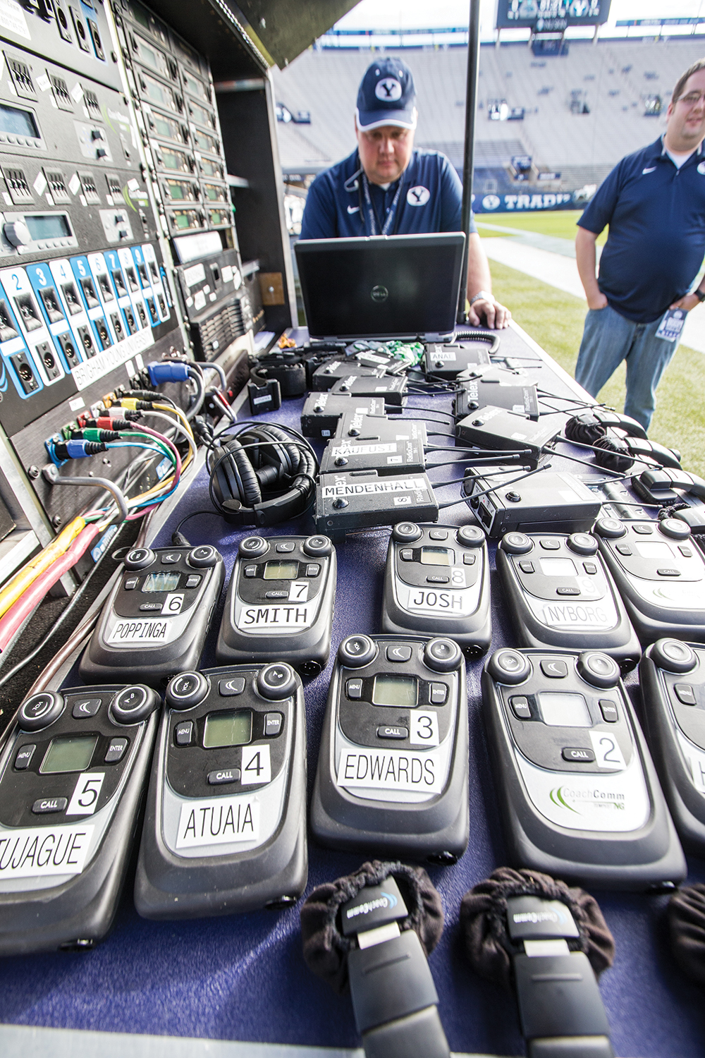 BYU's headset coordinator examines the coaches' radios before a football game kickoff.