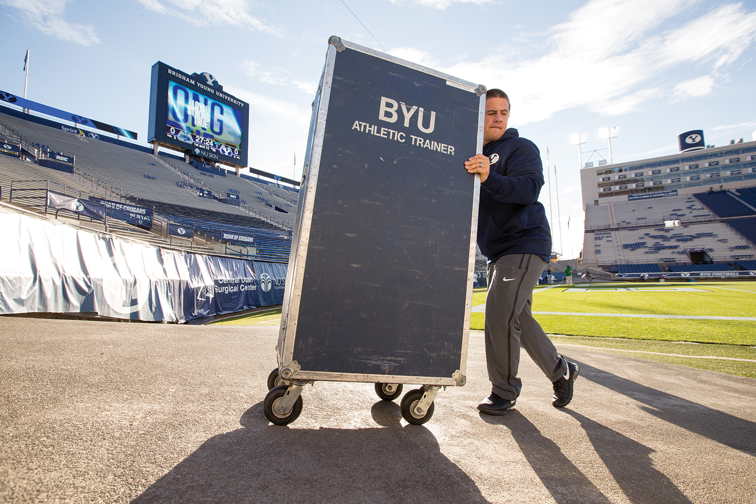 An athletic trainer moves equipment to the football field in preparation for kickoff.