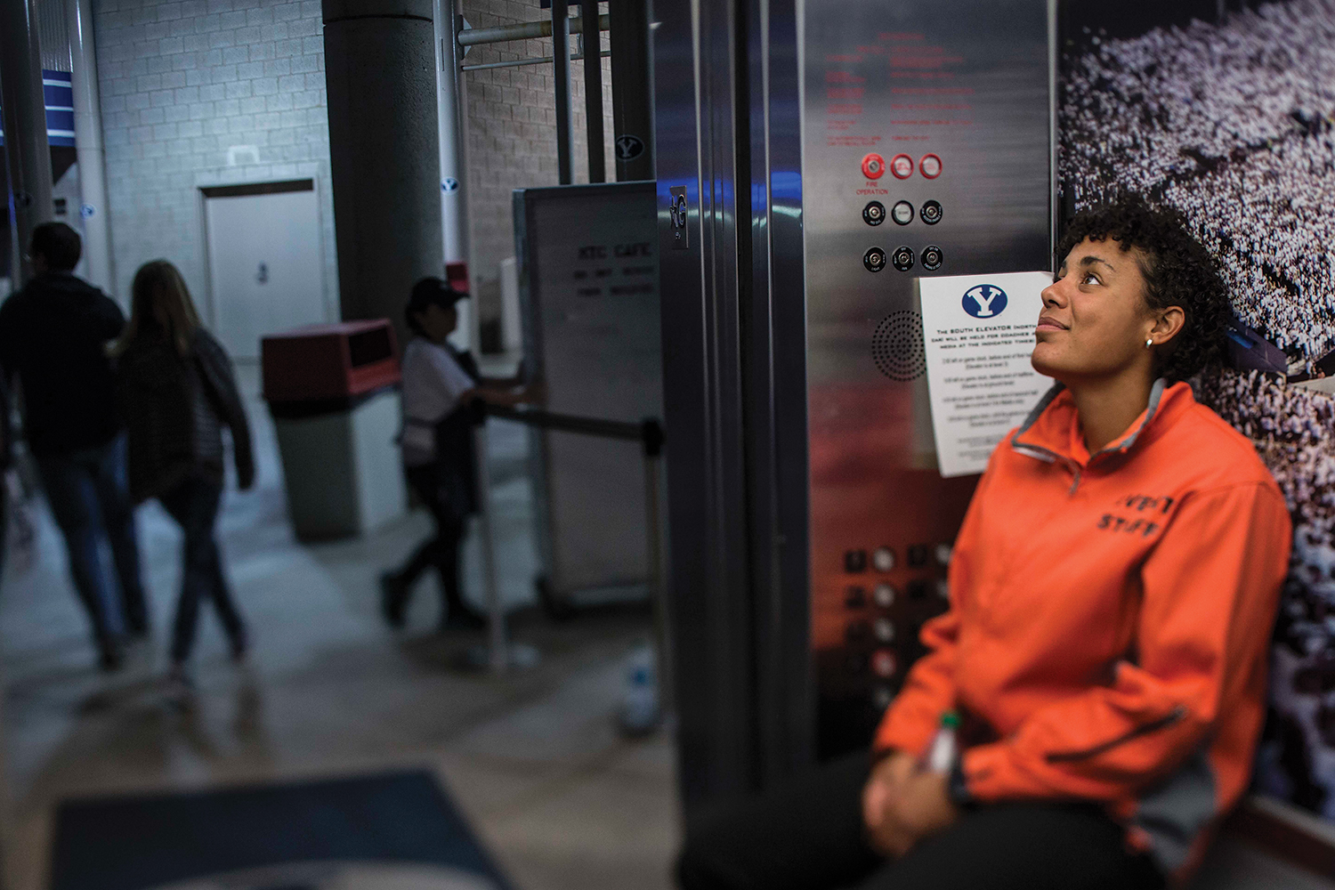 A BYU student elevator operator listens to the game audio as she waits inside the elevator.