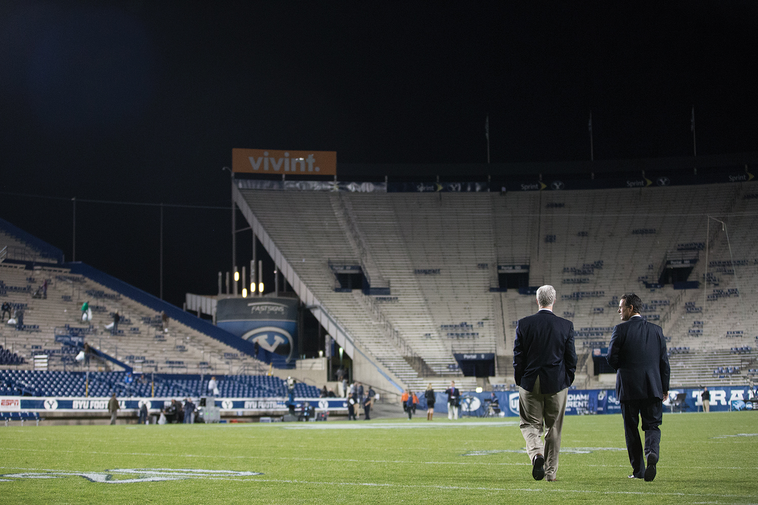 BYU's president and a vice president stroll across the field after a football game.