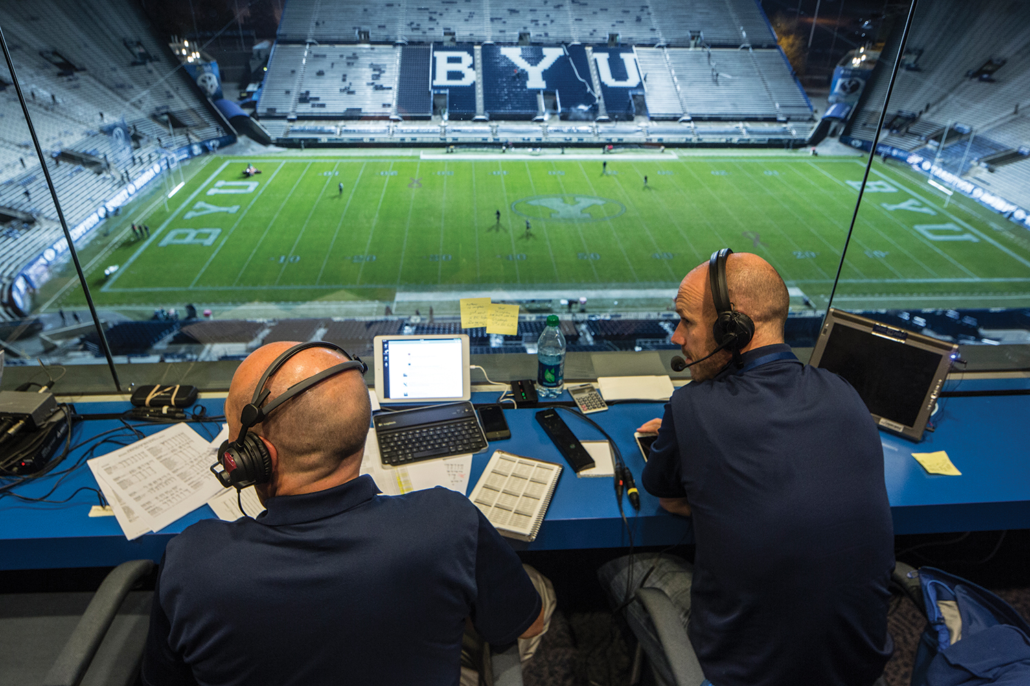 Greg Wrubell, the Voice of the Cougars, and one of his broadcasting partners discuss the game high over the LaVell Edwards Stadium field.