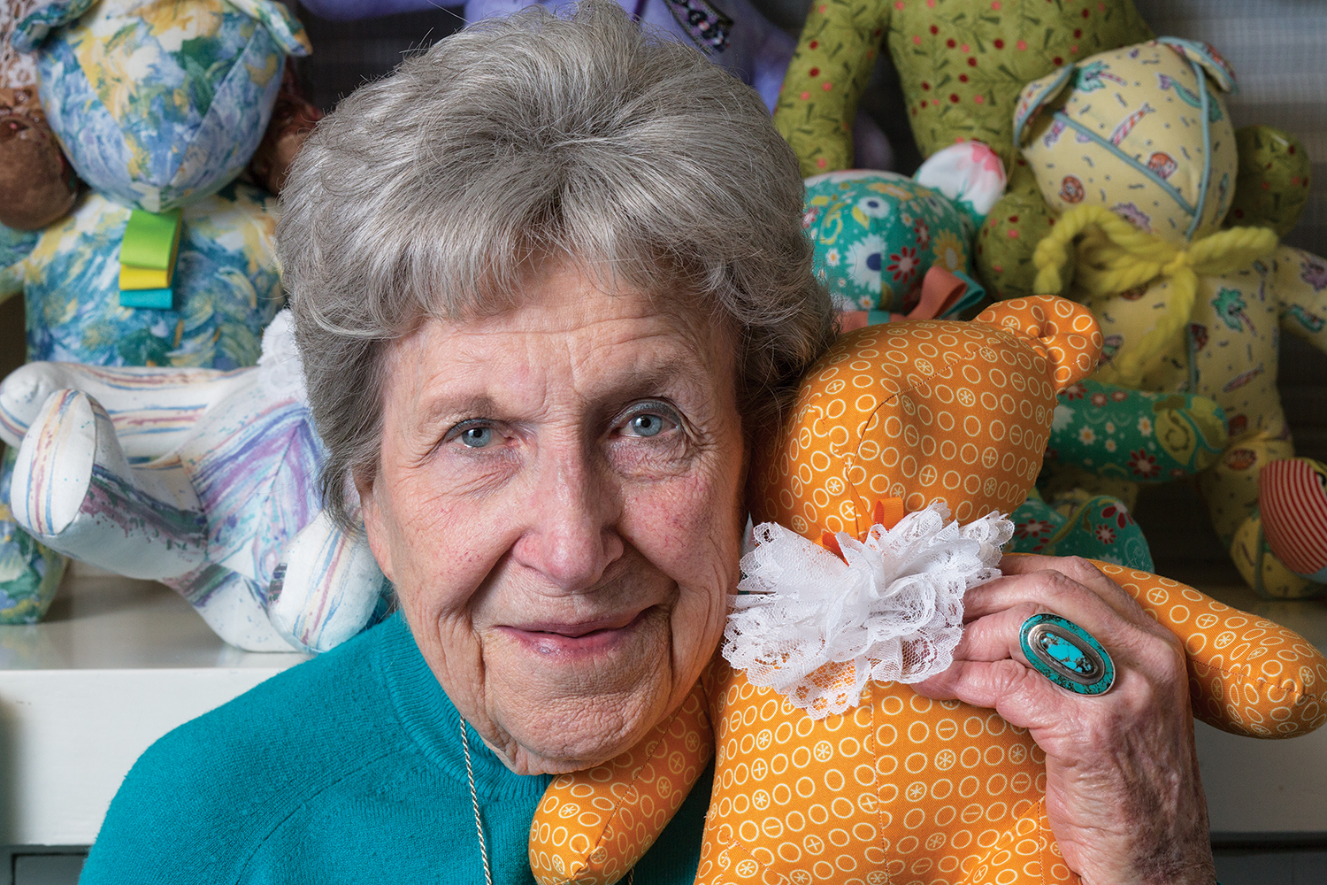 Ruth Brasher holding one of her home made teddy bears. There are other bears in the background.