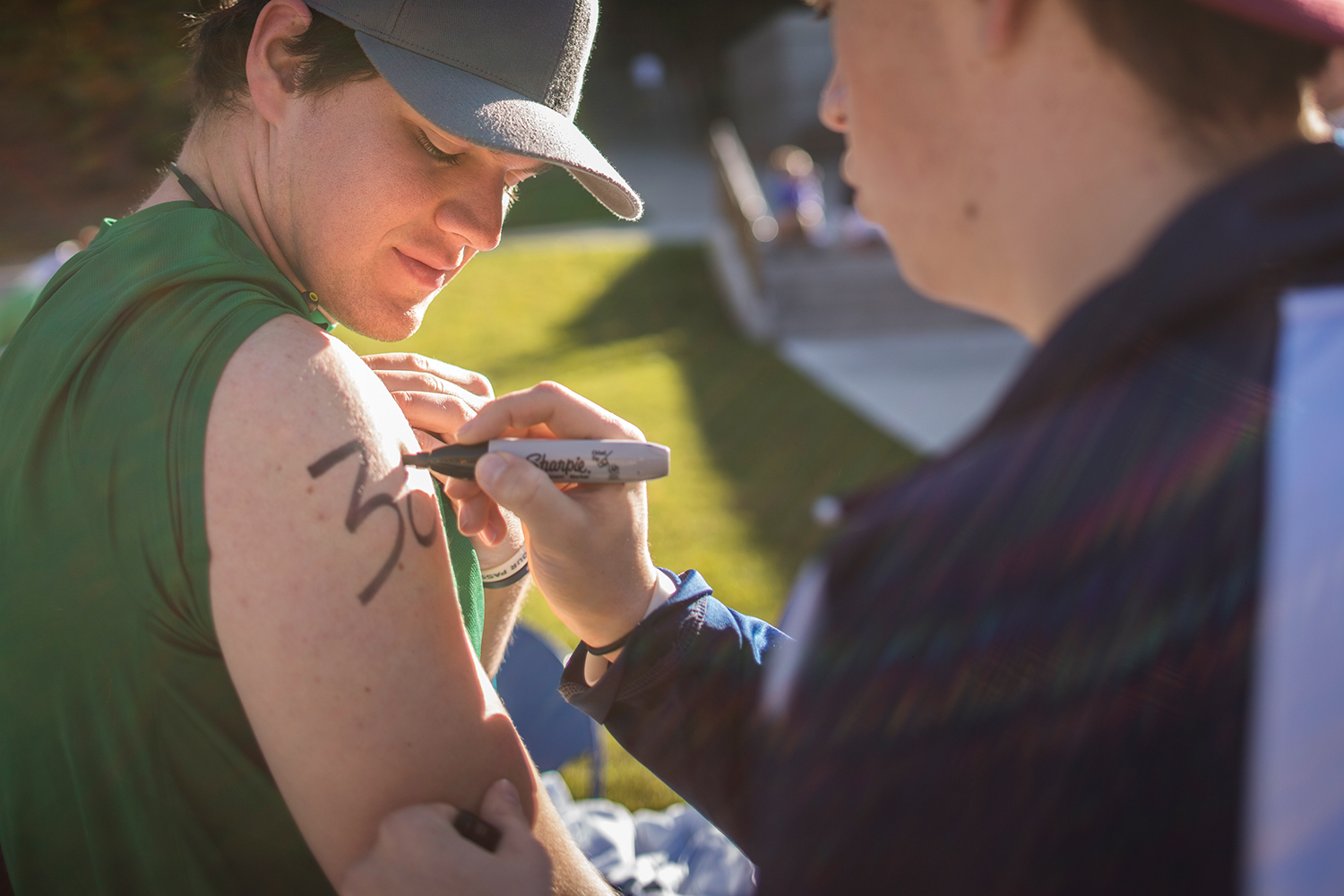 A triathlon participant is having his participant number drawn on his arm with a Sharpie.