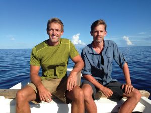 Jeffry Flake and Martin Heinrich sitting on a boat in a large body of water.