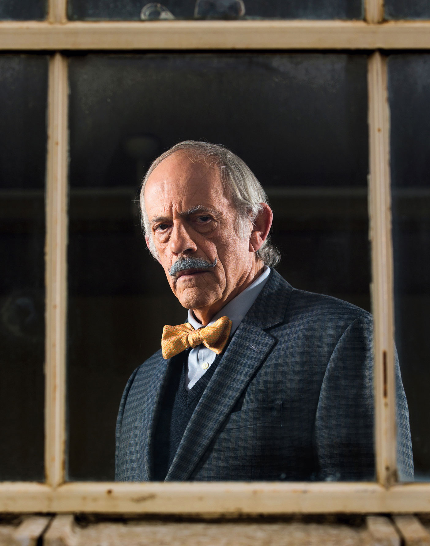 Christopher Lloyd poses as Professor Stanley Hargraves looking through a window