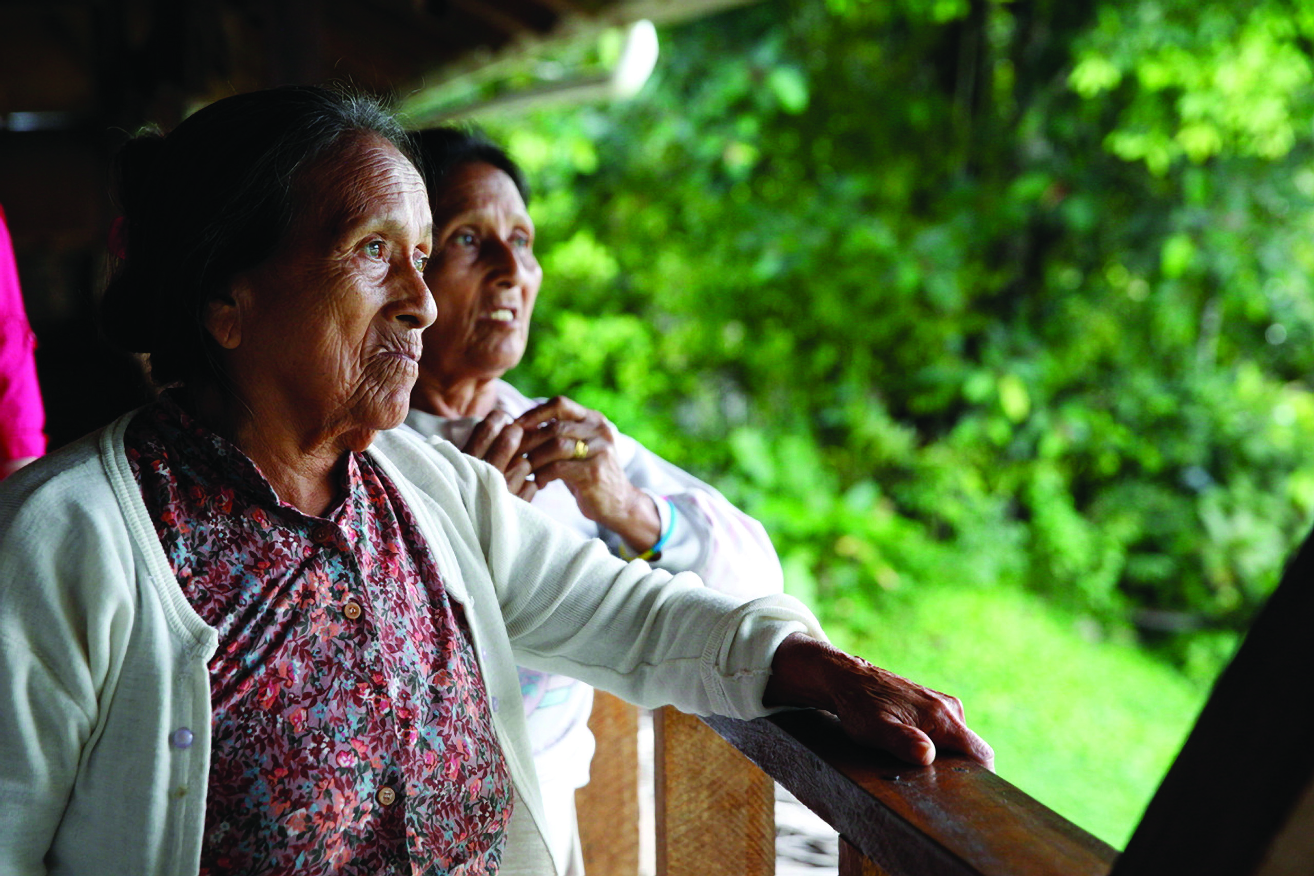 Luisa and Elodia stand together looking out of the open-air hut