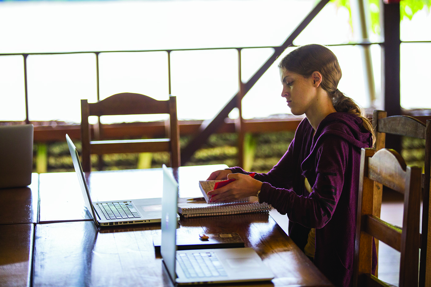 A student types on her laptop while sitting in the open-air field school