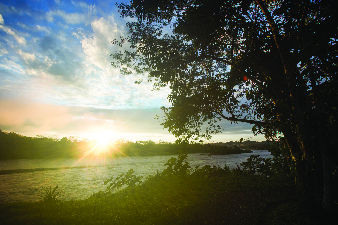 Sunlight breaks over the horizon across the river