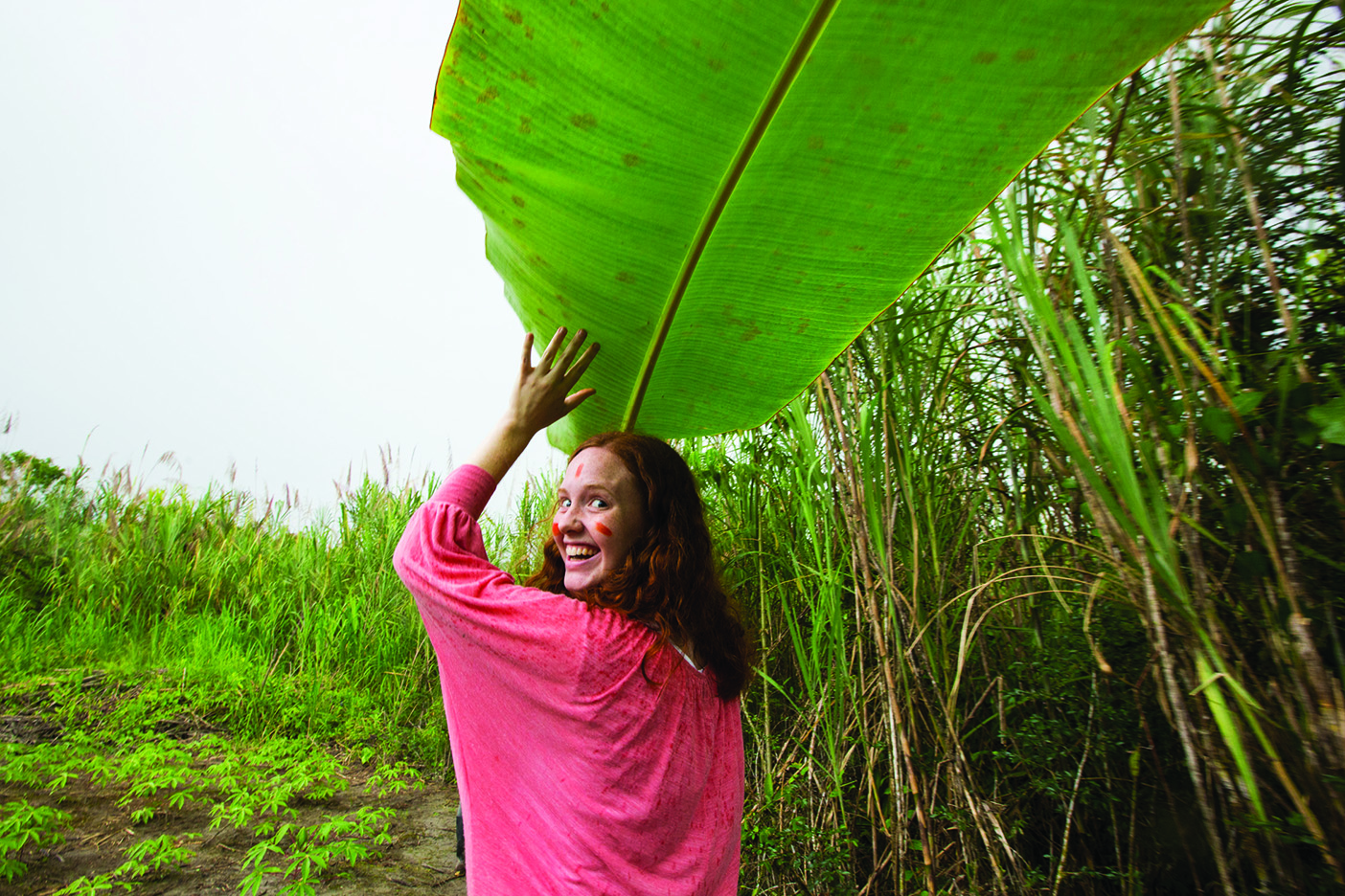 student Sydney Jensen finds shelter from a passing storm under a banana leaf