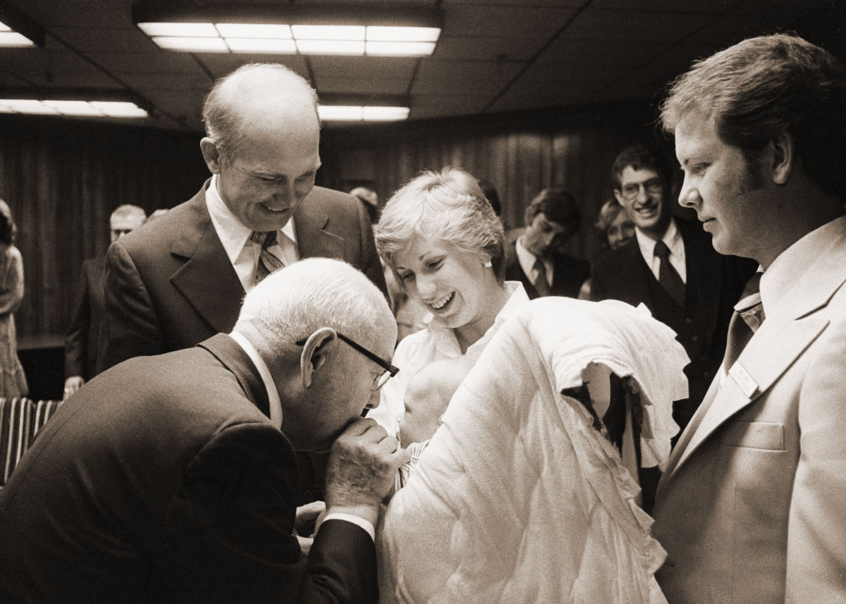 President Kimball kisses a baby before a BYU devotional.