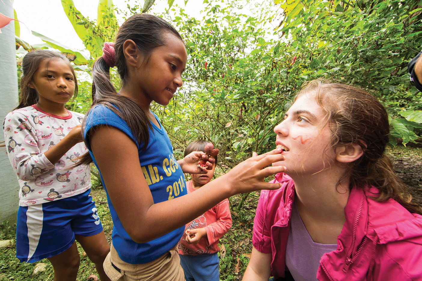 Two Ecuadorian girls paint the face of a BYU student