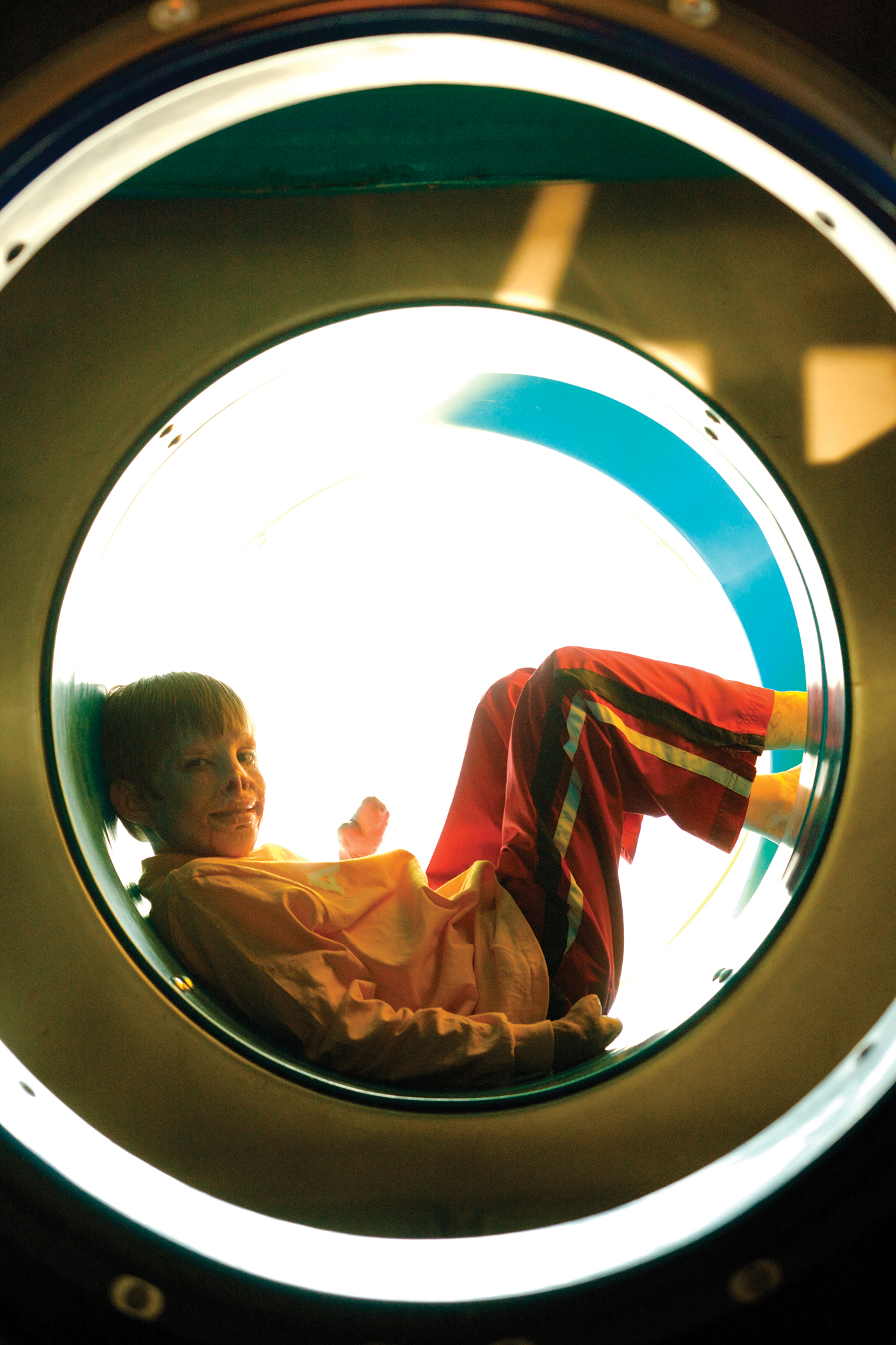 Marius sitting in a circle structure, wearing a yellow jacket and red pants