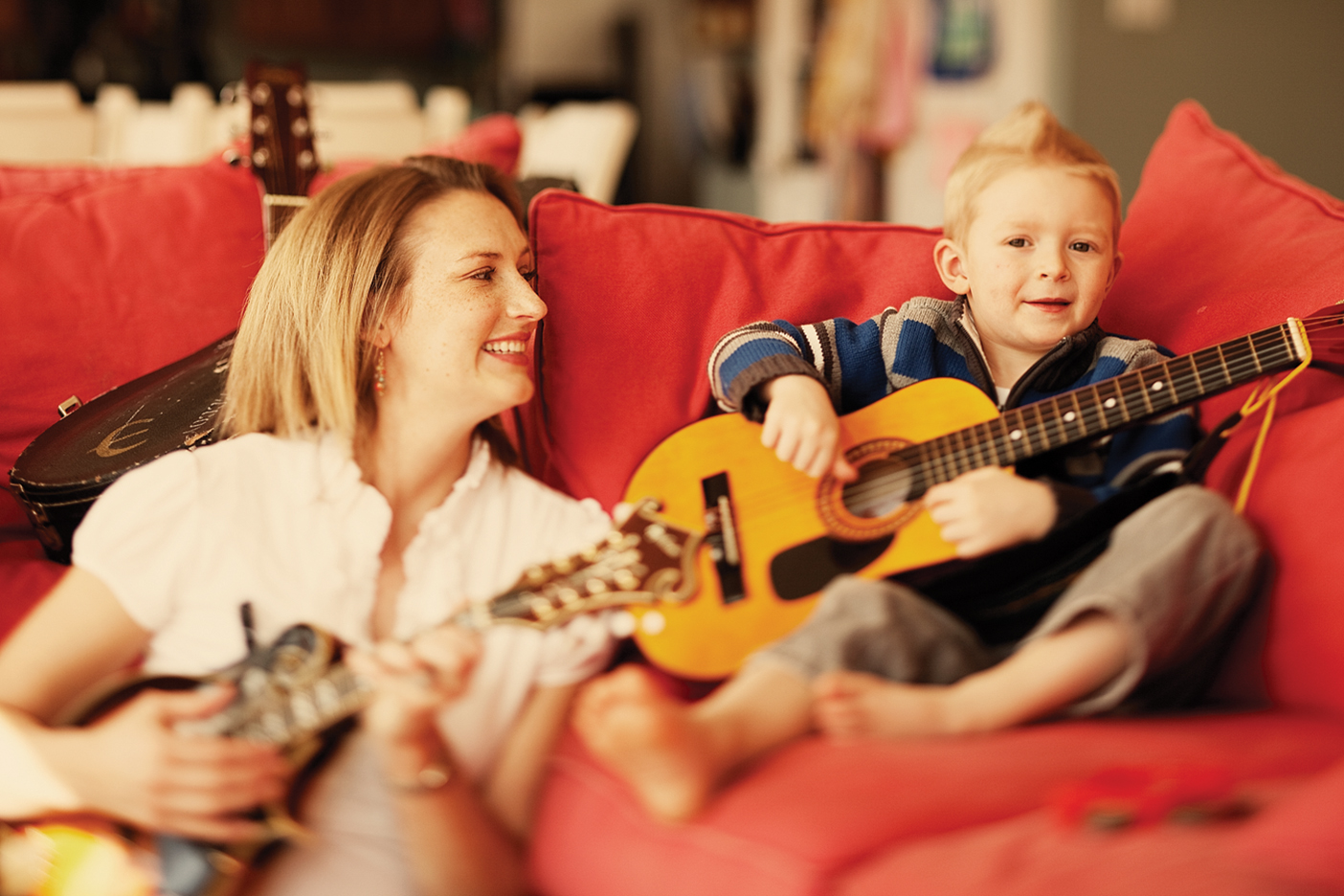 a mother helps her young son play the guitar