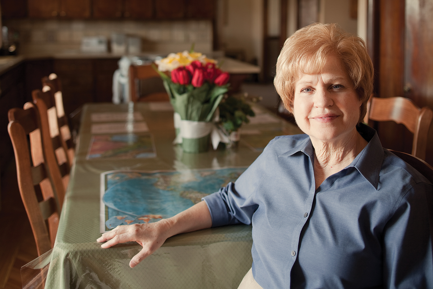 a woman sits at the table, smiling at the camera