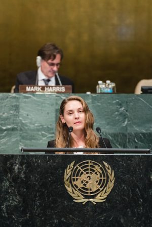 Jamie D. Clegg standing behind podium in the United Nations assembly room.