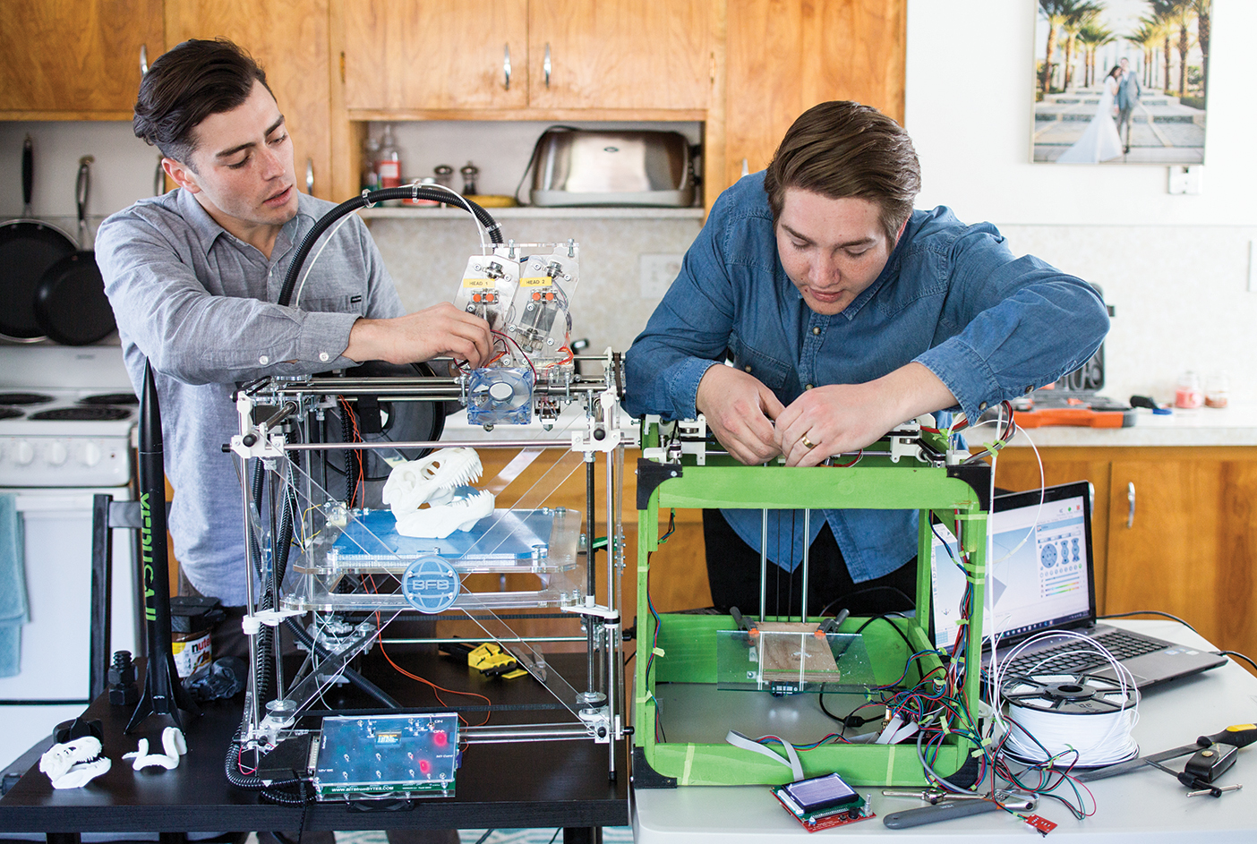 Scott Harris and Ryan Garrison hover over their 3-D printer