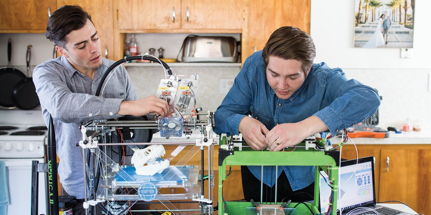 Scott Harris and Ryan Garrison hover over their 3-D printer