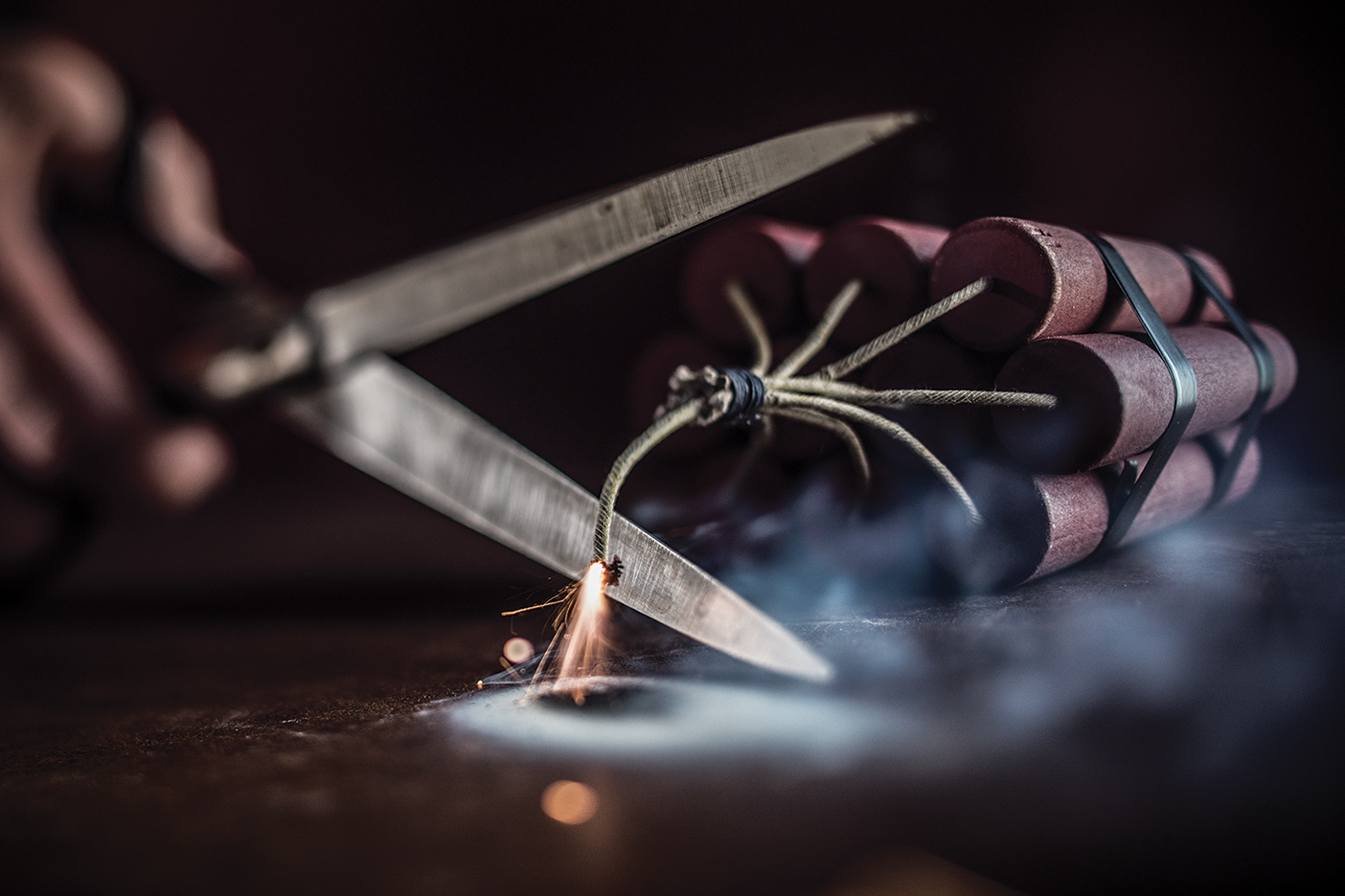 Scissors cut the wick on a stick of dynamite, preventing it from exploding.