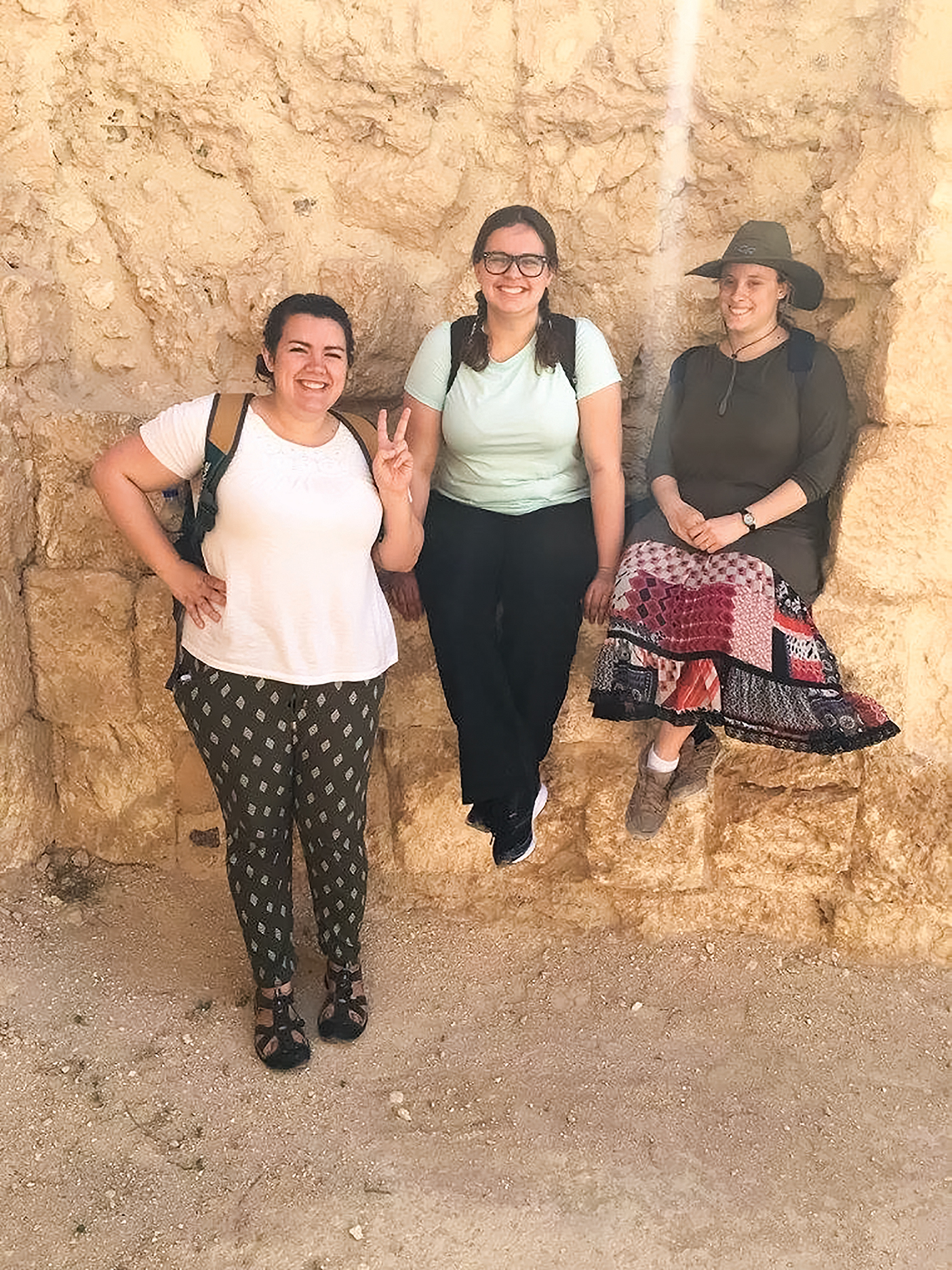 Hannah Lambert and friends stand in front of rock in hiking gear