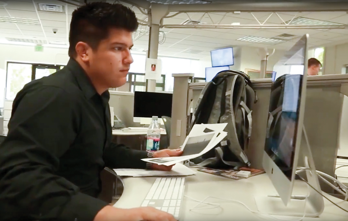 Gianluca Cuestas sitting at a desk with his backpack