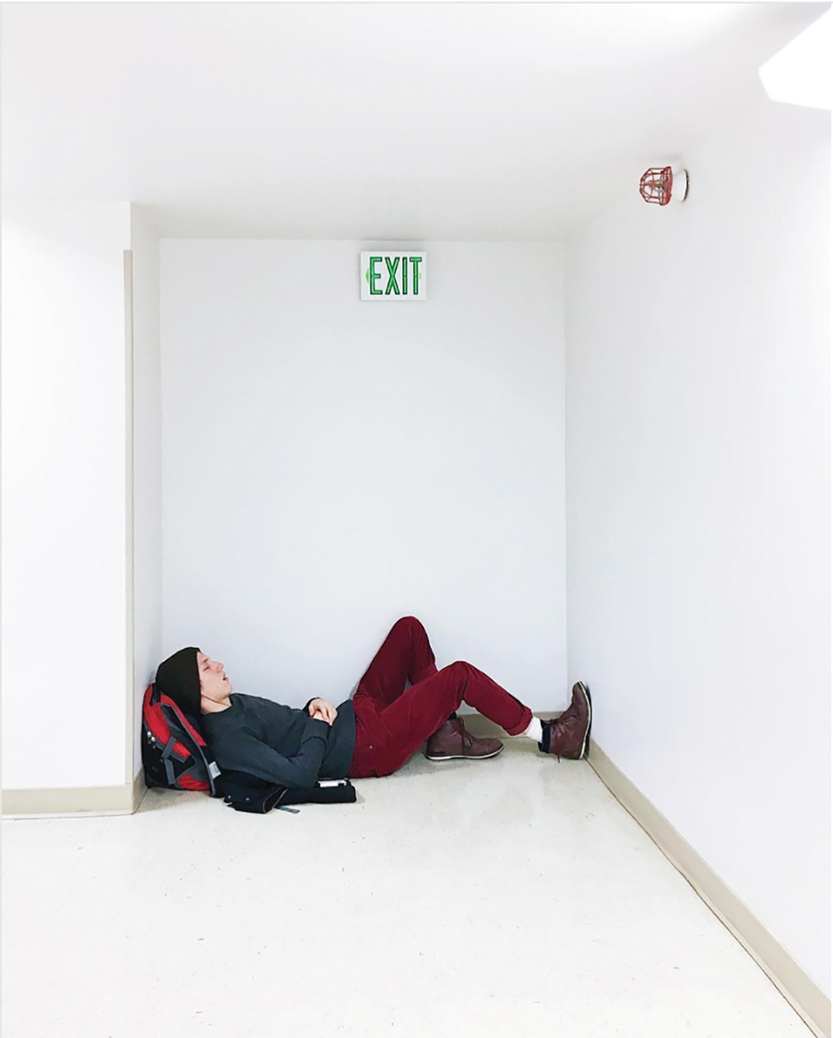 student talking a nap on the floor using their backpack as a pillow