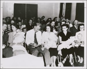 a black and white picture of rows of parents holding babies