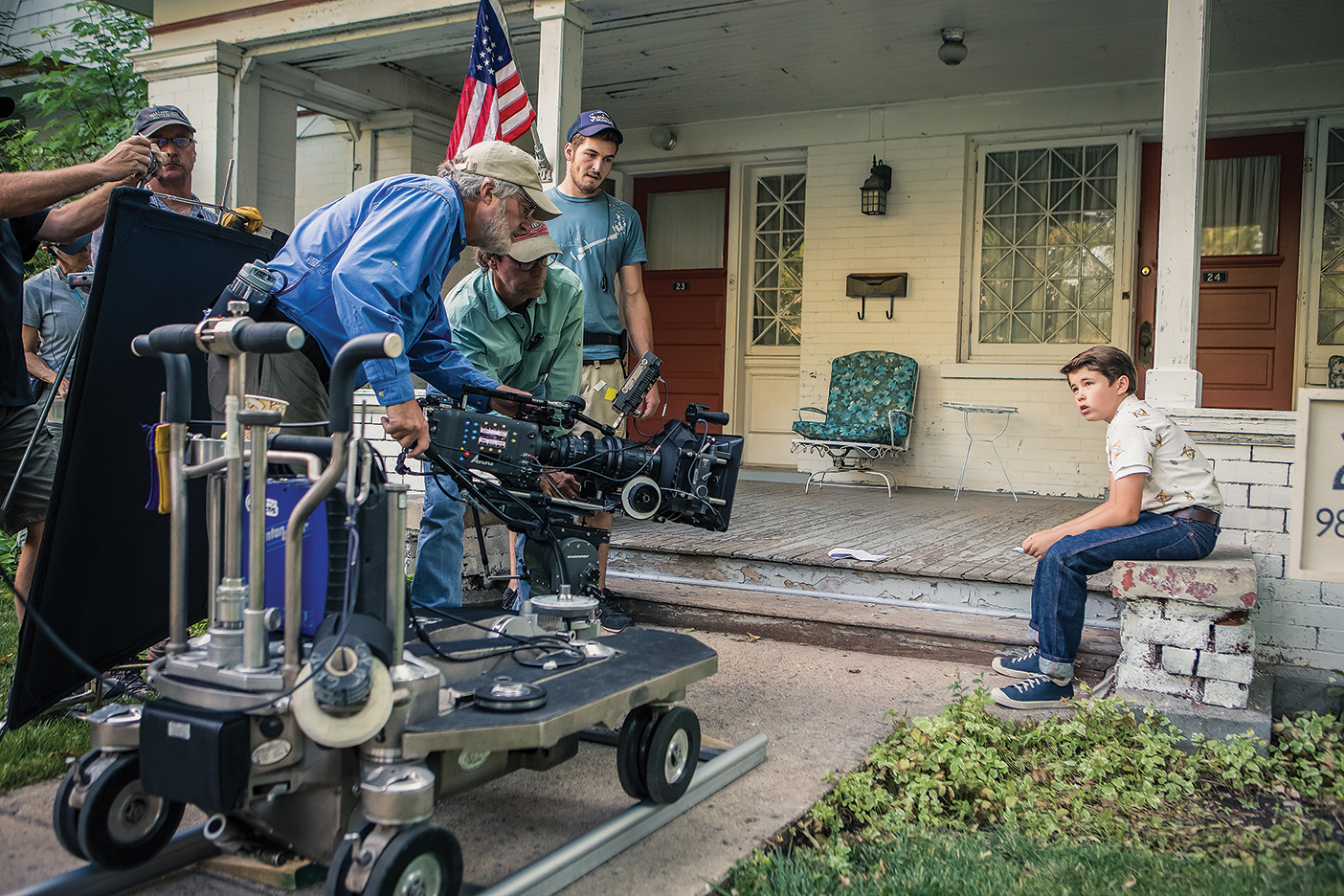 crews film a young boy sitting on a porch
