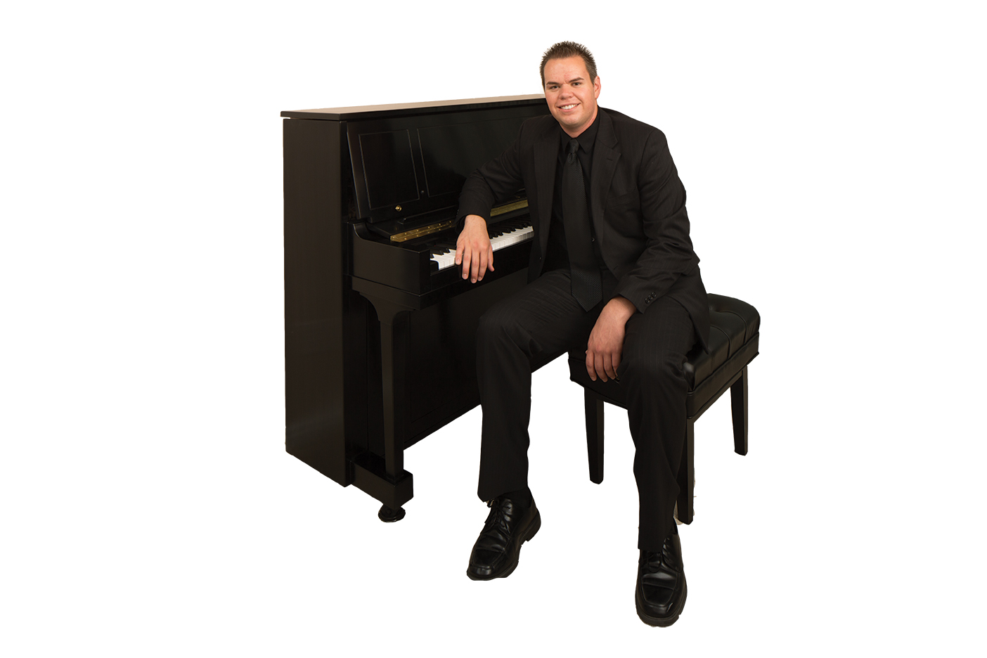 Conlan Miller sitting on a piano bench next to an upright piano