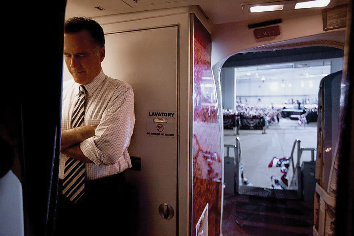 Romney folds his arms and hows his head in prayer before exiting a plane during his campaign