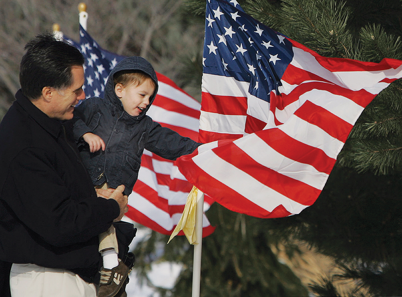 Mitt Romney holds his young grandson as he touches an American flag