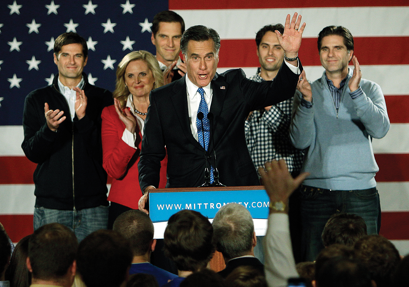 Romney waves to a crowd as his family stands behind him during his presidential campaign.
